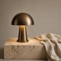 Aetheris Atelier Cordless Anodized-Bronze Mushroom Dome Architectural Nightstand Lamp with downward glare-free reflection on travertine