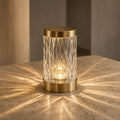 Aetheris Atelier Crystal-Prism Refracting Cordless Architectural Table Lantern projecting geometric caustic light patterns on travertine